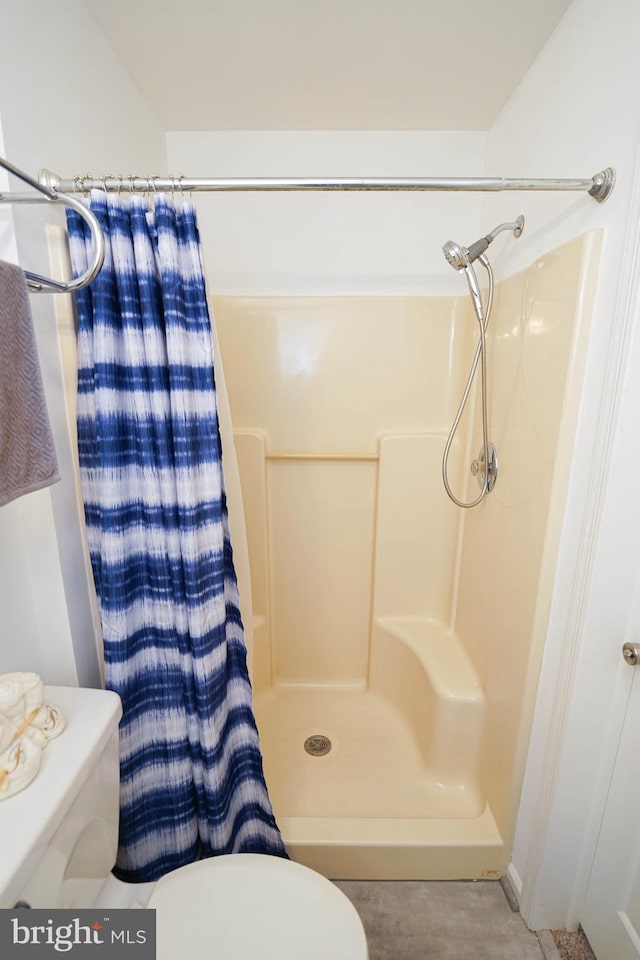 bathroom with toilet, tile flooring, and a shower with curtain