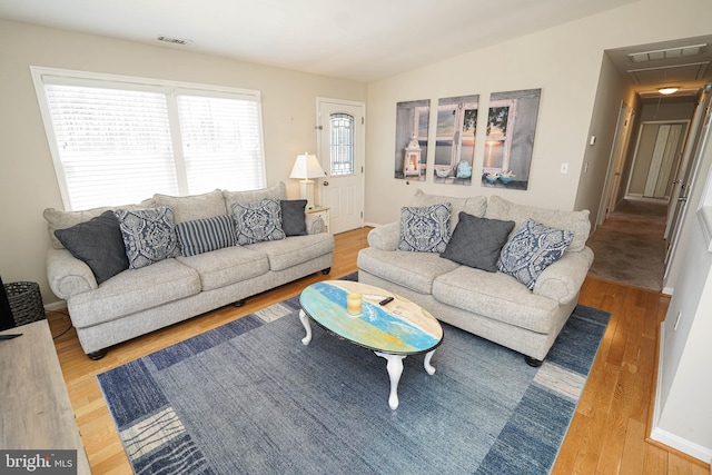 living room with lofted ceiling, light wood-type flooring, and a wealth of natural light