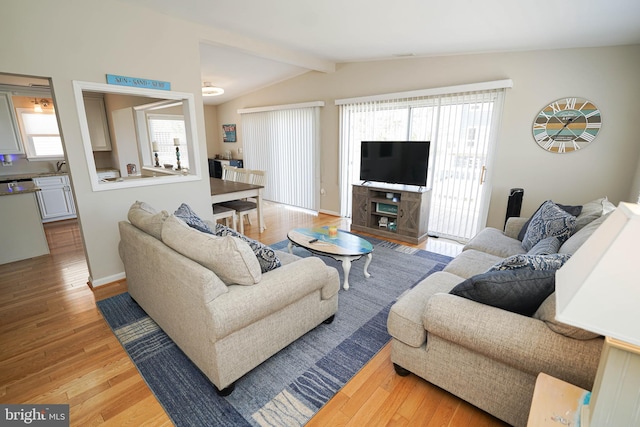 living room with a wealth of natural light, lofted ceiling, light hardwood / wood-style flooring, and a fireplace