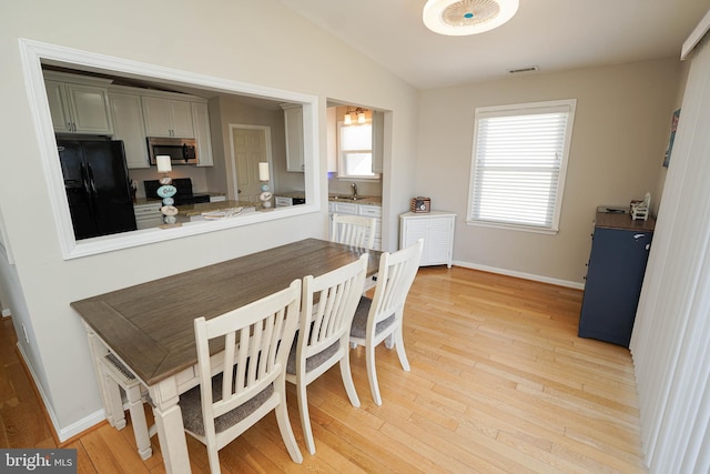 dining room with vaulted ceiling, light hardwood / wood-style floors, and sink