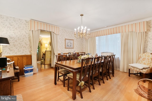 dining space featuring crown molding, wooden walls, light hardwood / wood-style floors, and a notable chandelier