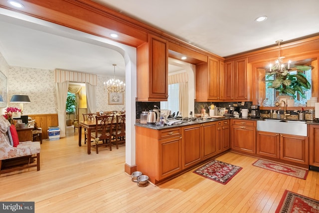 kitchen featuring pendant lighting, a chandelier, sink, and light hardwood / wood-style flooring