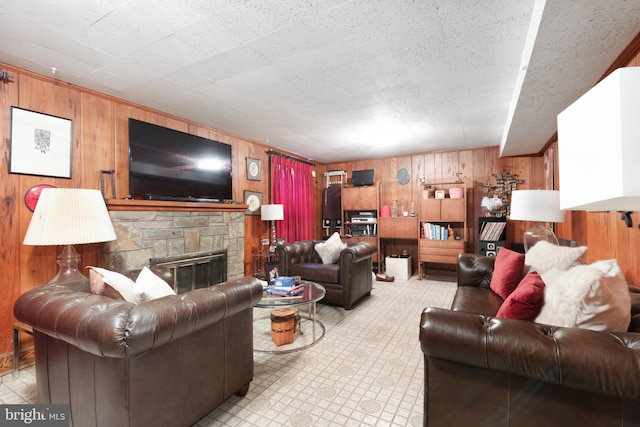 living room with a stone fireplace and wood walls