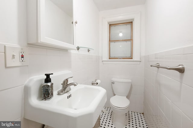 bathroom featuring tile patterned flooring, toilet, sink, and tile walls