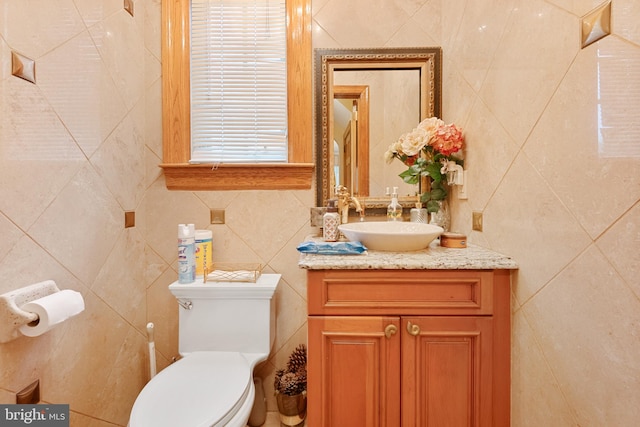 bathroom with vanity, tile walls, and toilet