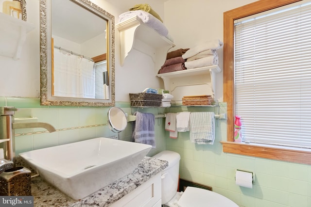 bathroom with vanity, toilet, and tile walls