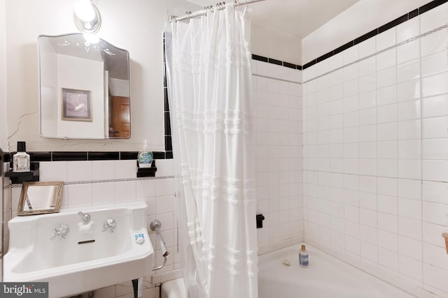 bathroom featuring sink, tile walls, and shower / tub combo with curtain