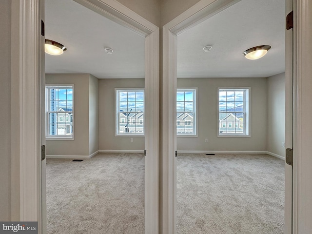 unfurnished room featuring light carpet and plenty of natural light