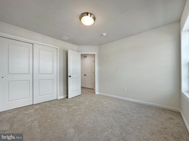 unfurnished bedroom featuring light colored carpet and a closet