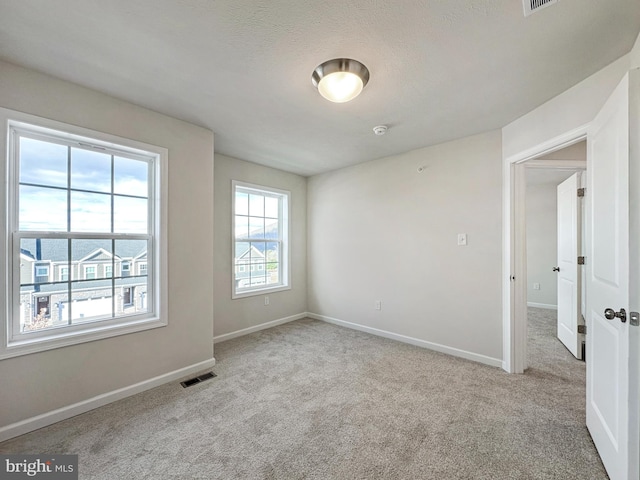 unfurnished room with a textured ceiling and light carpet