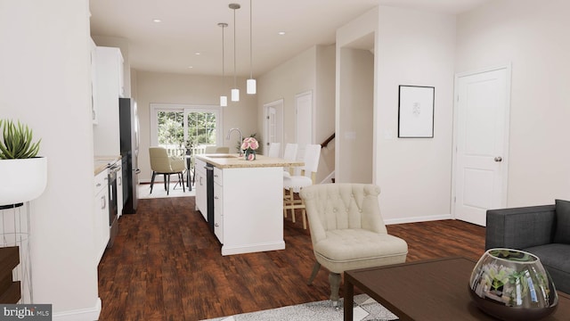 kitchen featuring pendant lighting, white cabinets, an island with sink, and dark wood-type flooring