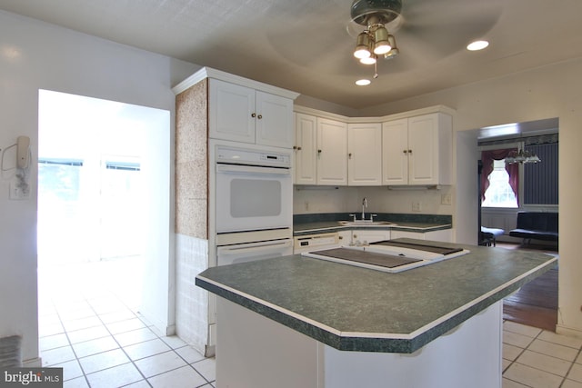 kitchen featuring white cabinets, ceiling fan, a healthy amount of sunlight, and light tile floors