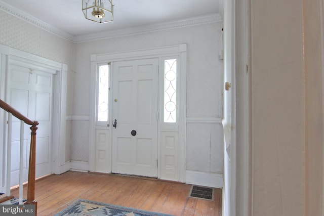 foyer entrance with ornamental molding and light hardwood / wood-style flooring