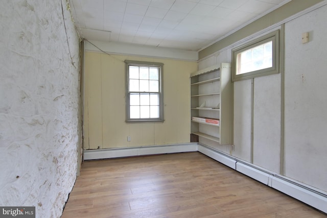 unfurnished room featuring light hardwood / wood-style floors and a baseboard heating unit