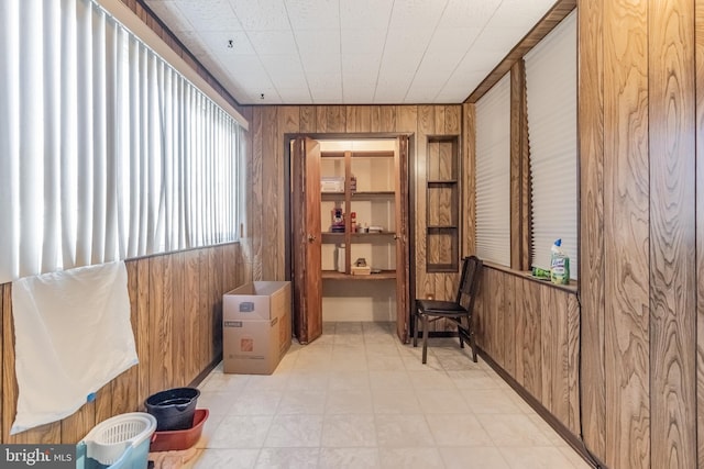 living area with light tile floors and wooden walls