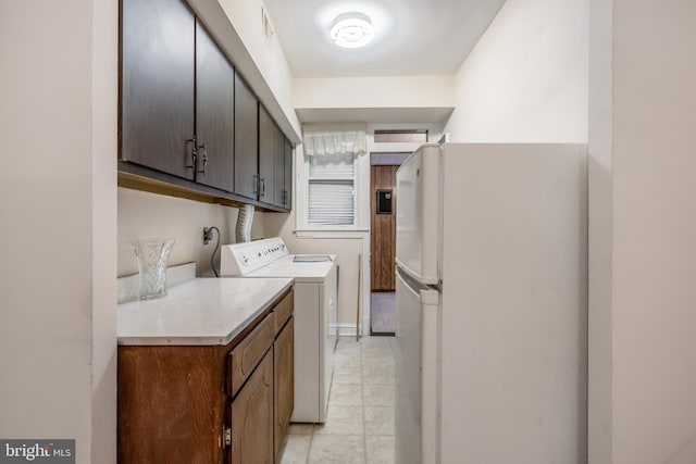 kitchen with dark brown cabinets, white fridge, light tile floors, and washer and dryer