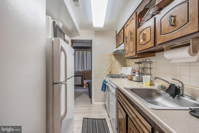 kitchen with range, sink, tasteful backsplash, light wood-type flooring, and white refrigerator