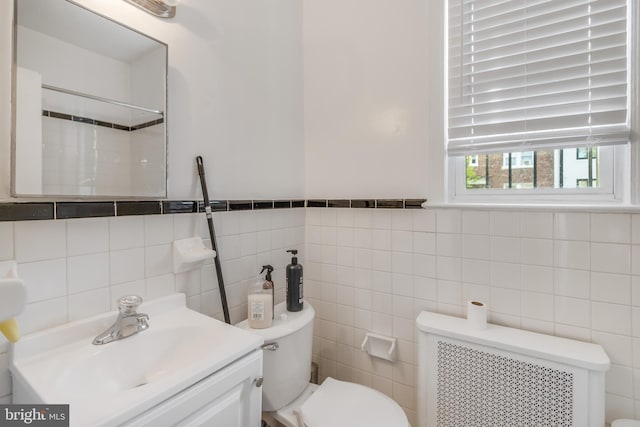 bathroom featuring tile walls, vanity, toilet, and radiator heating unit