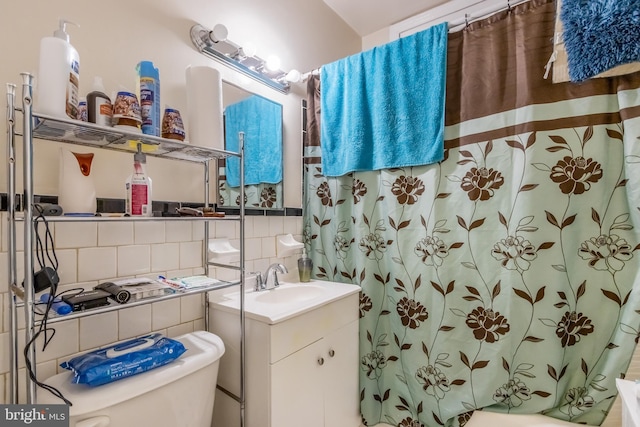 bathroom featuring backsplash, toilet, tile walls, and large vanity