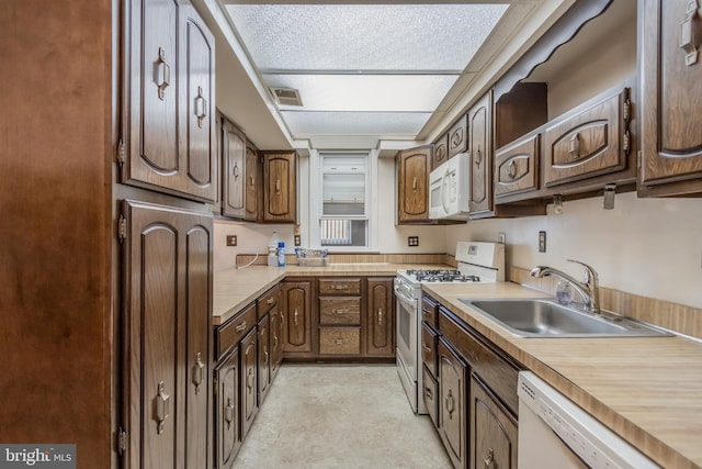 kitchen featuring white appliances, sink, and dark brown cabinetry