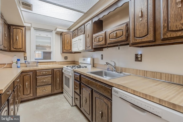 kitchen with dark brown cabinetry, white appliances, and sink