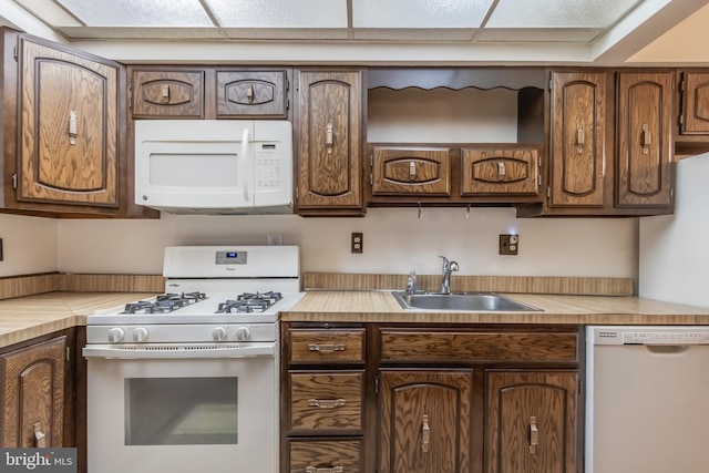 kitchen with a paneled ceiling, white appliances, and sink