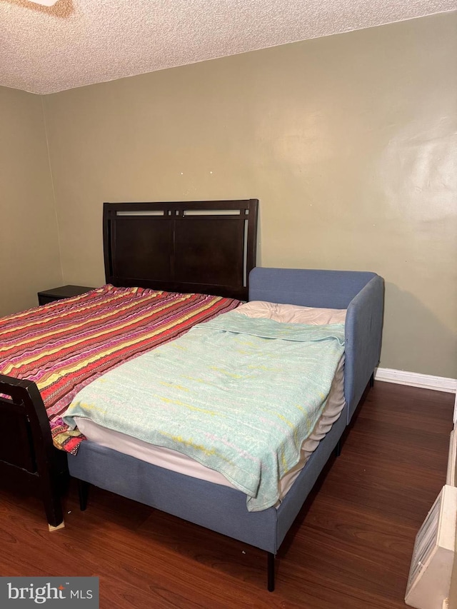 bedroom featuring a textured ceiling and dark hardwood / wood-style floors