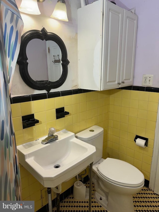 bathroom with toilet, sink, tile walls, and decorative backsplash