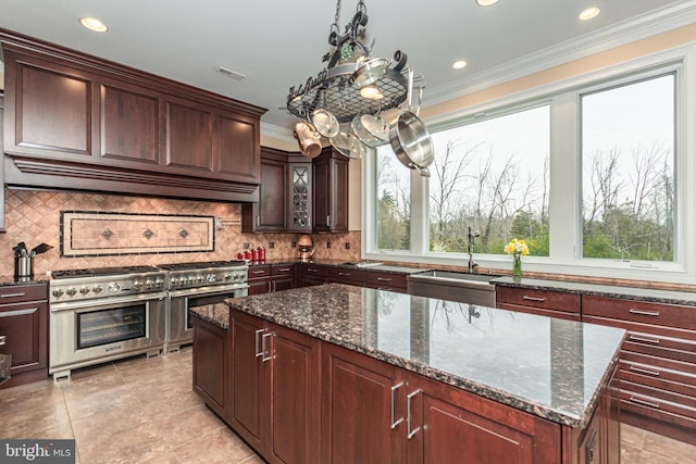 kitchen featuring a wealth of natural light, custom range hood, range with two ovens, and a sink