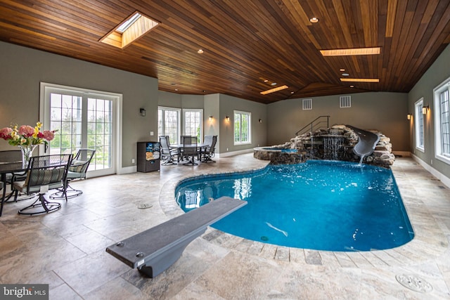 view of pool featuring a skylight, a water slide, and a diving board