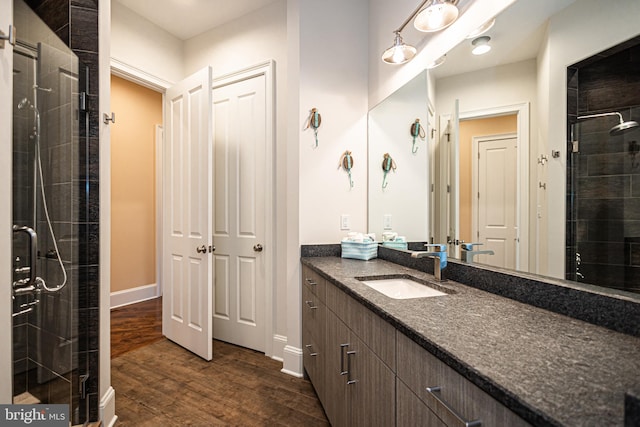 bathroom featuring a shower stall, baseboards, wood finished floors, and vanity