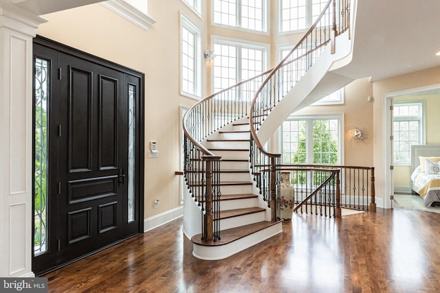 foyer with stairway, a high ceiling, baseboards, and wood finished floors