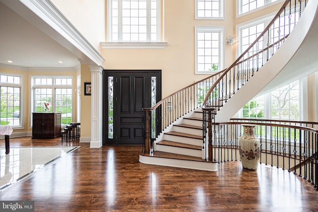 foyer entrance featuring crown molding, a towering ceiling, baseboards, and wood finished floors