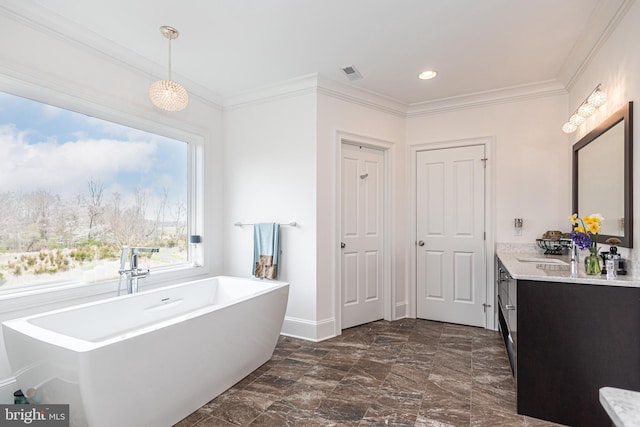 full bath with a freestanding tub, vanity, visible vents, baseboards, and ornamental molding