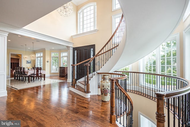 entrance foyer featuring ornamental molding, wood finished floors, a high ceiling, and an inviting chandelier