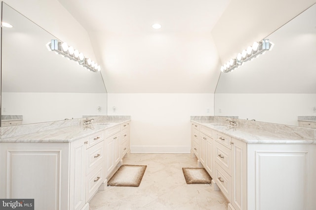 full bath featuring lofted ceiling, a sink, two vanities, and baseboards