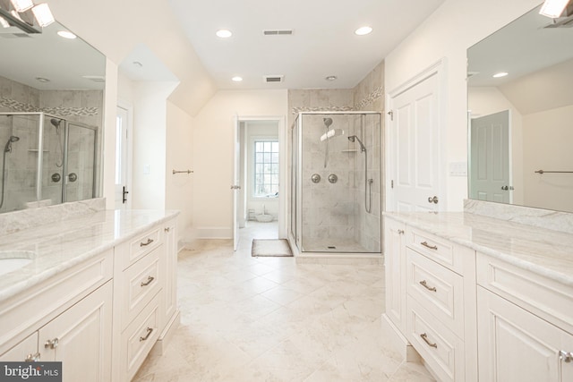 bathroom with a shower stall, visible vents, and two vanities