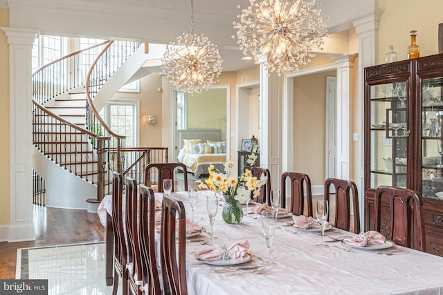 dining area with crown molding, decorative columns, stairway, an inviting chandelier, and wood finished floors