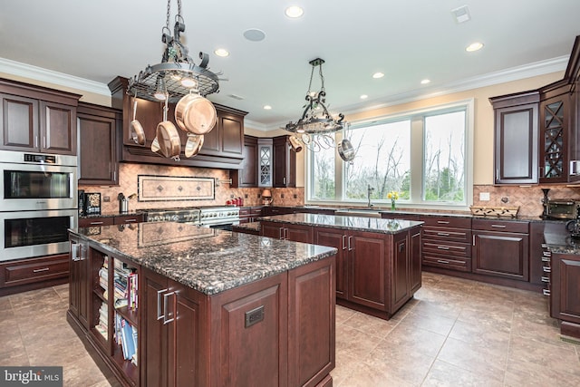 kitchen featuring double oven, a sink, a kitchen island, dark stone countertops, and glass insert cabinets