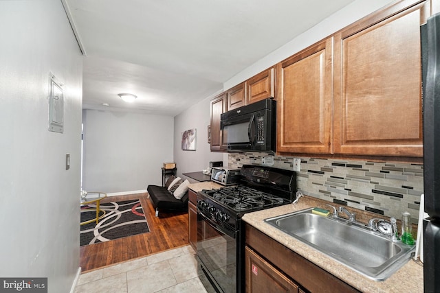 kitchen featuring black appliances, light hardwood / wood-style flooring, backsplash, and sink