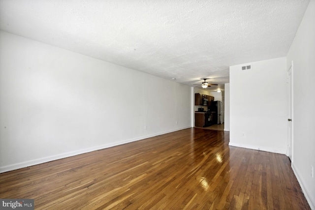 empty room with a textured ceiling, ceiling fan, and dark hardwood / wood-style flooring