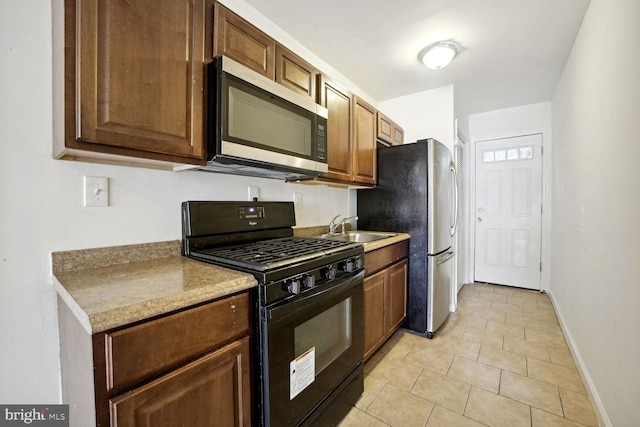 kitchen with appliances with stainless steel finishes, light tile patterned floors, and sink