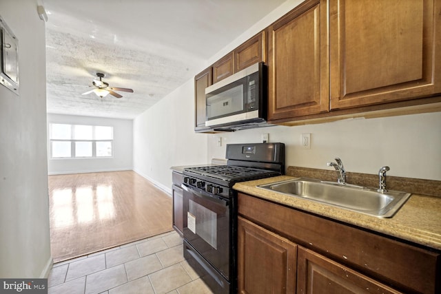 kitchen featuring a textured ceiling, black range with gas cooktop, light hardwood / wood-style floors, sink, and ceiling fan