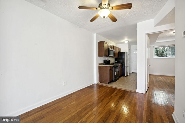 unfurnished living room featuring light wood-type flooring, ceiling fan, and a textured ceiling