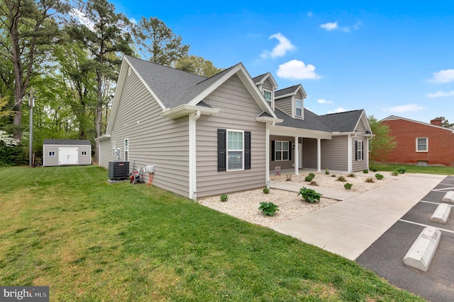 view of front of house with central AC, a front lawn, and a shed