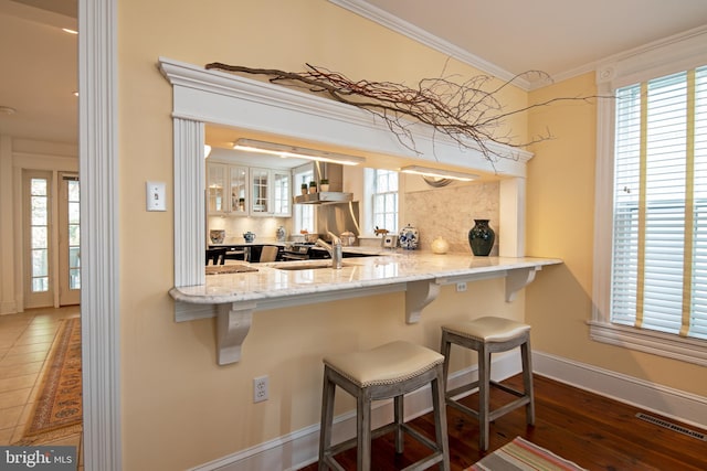 kitchen with plenty of natural light, backsplash, wall chimney exhaust hood, and a breakfast bar area