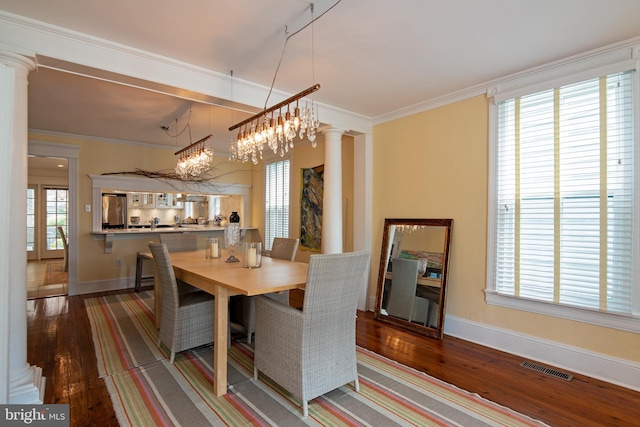 dining area with a chandelier, crown molding, wood-type flooring, and decorative columns