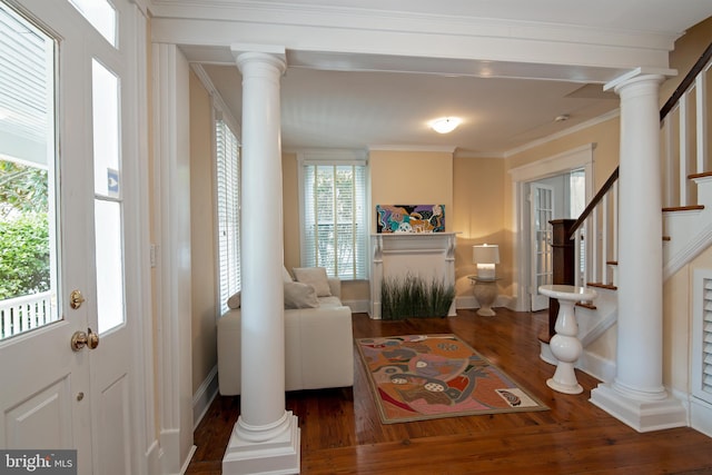 foyer featuring crown molding, dark wood-type flooring, and decorative columns