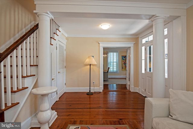 entrance foyer featuring dark hardwood / wood-style flooring, crown molding, and decorative columns