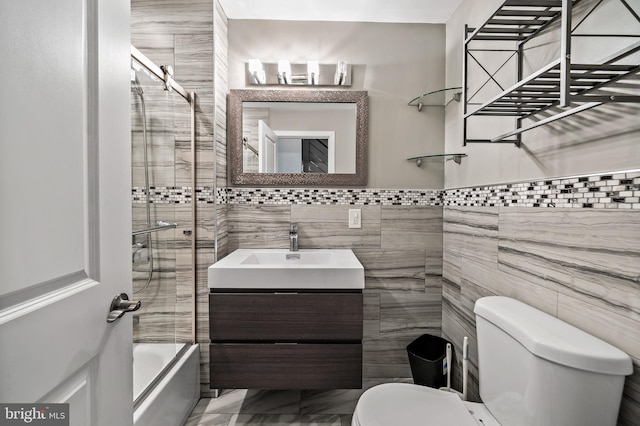 full bathroom featuring tile flooring, tile walls, enclosed tub / shower combo, toilet, and vanity